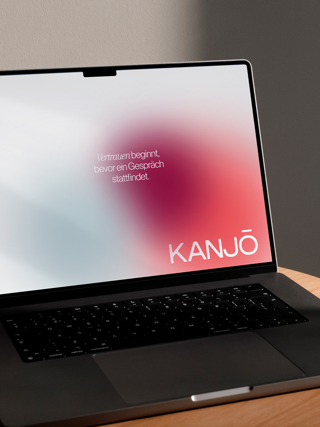 Laptop-Bildschirm mit rosa Farbverlauf und Kanjō-Logo – Webdesign